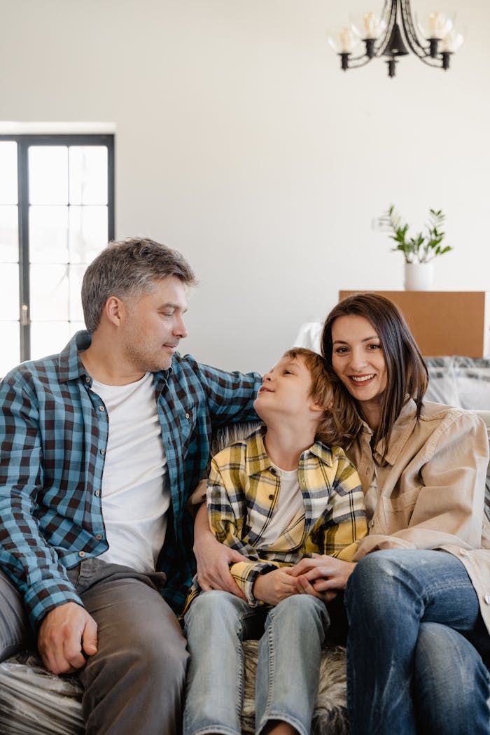 about-us A joyful family sitting together while unpacking in their new home living room.